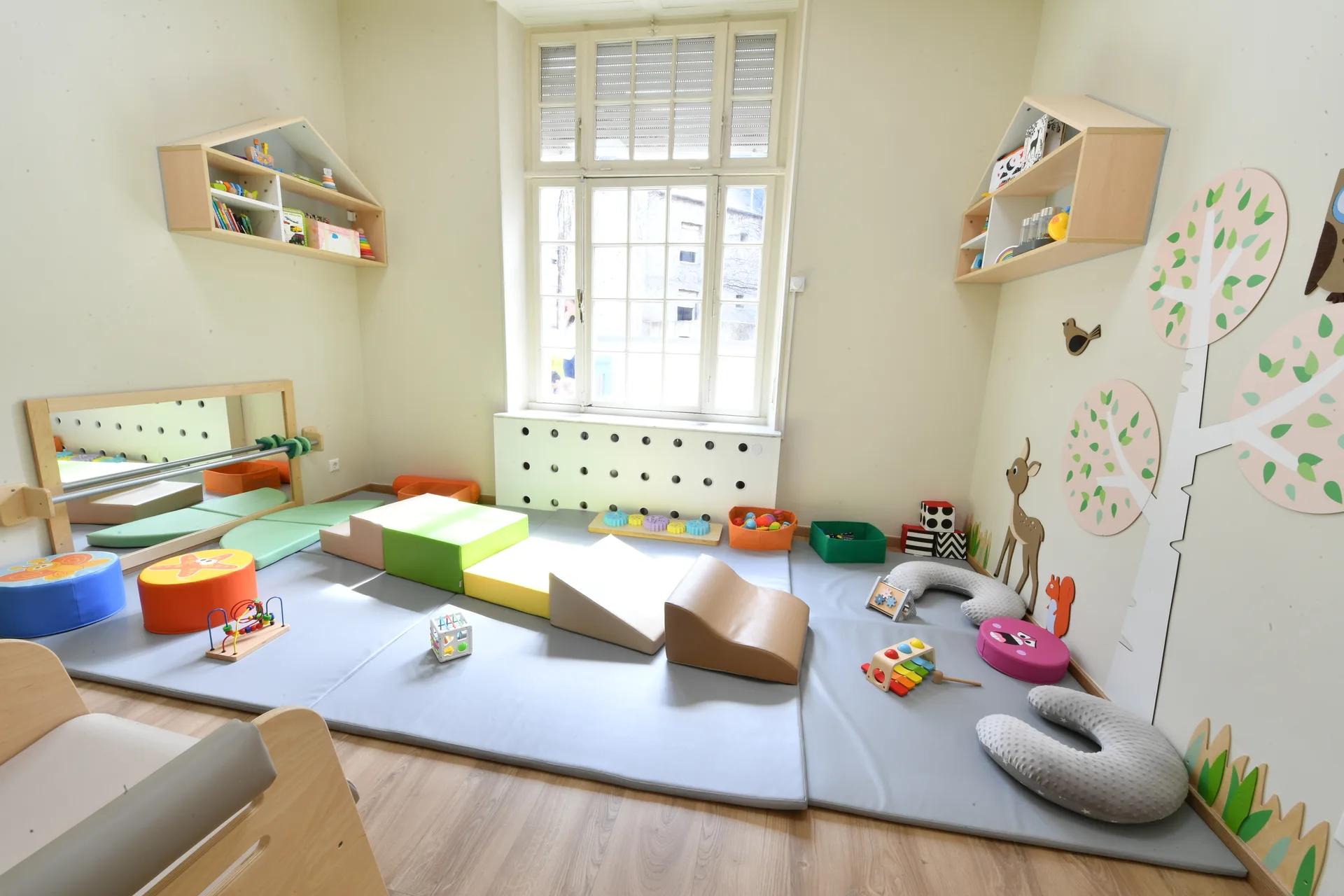 Espace bébés avec tapis de motricité, modules de mousse et barre d'appui à Differdange