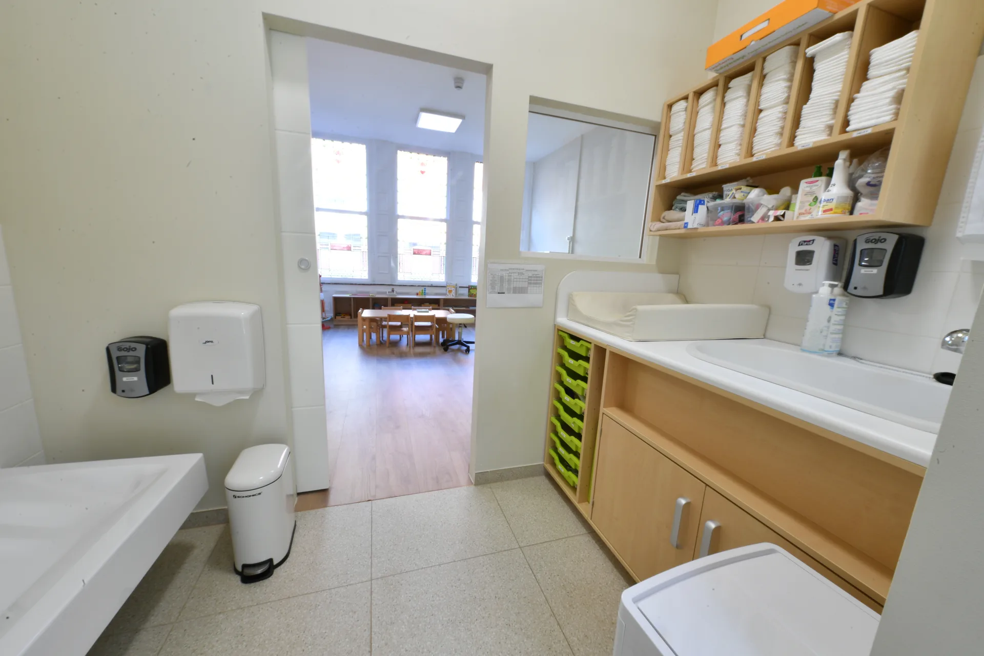 Espace de change avec plan lavable et rangements ouverts sur la salle de vie à Differdange