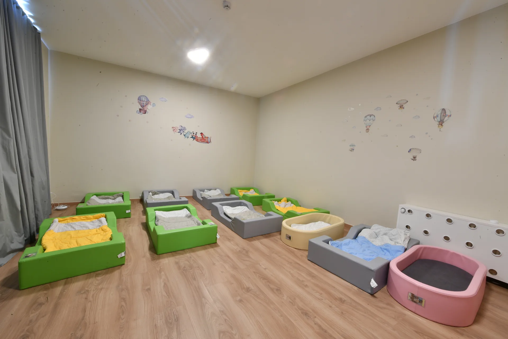 Dortoir douillet avec petits lits colorés et décor de montgolfières à la crèche de Differdange