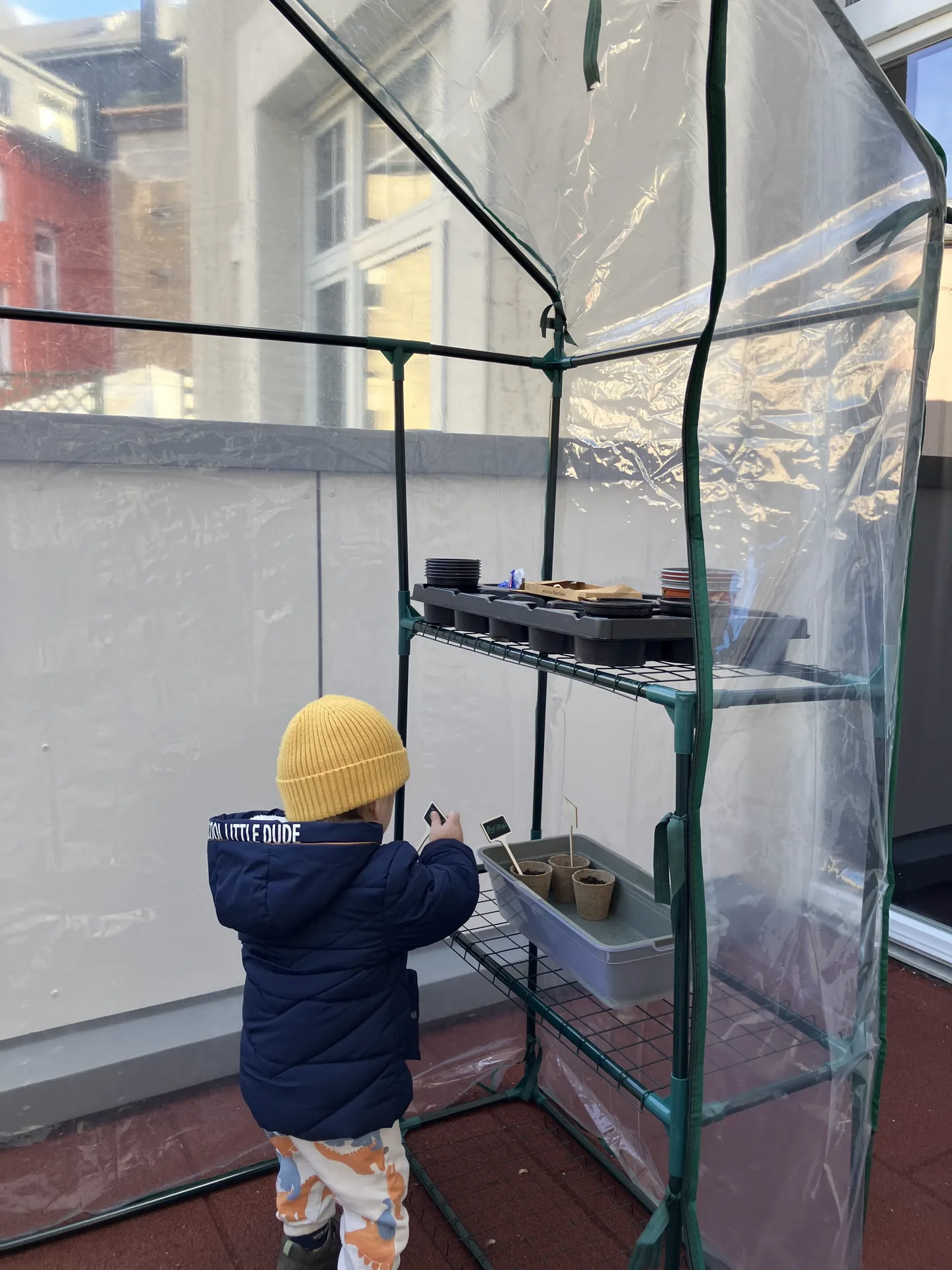 Enfant devant la mini-serre du potager de la crèche de Differdange