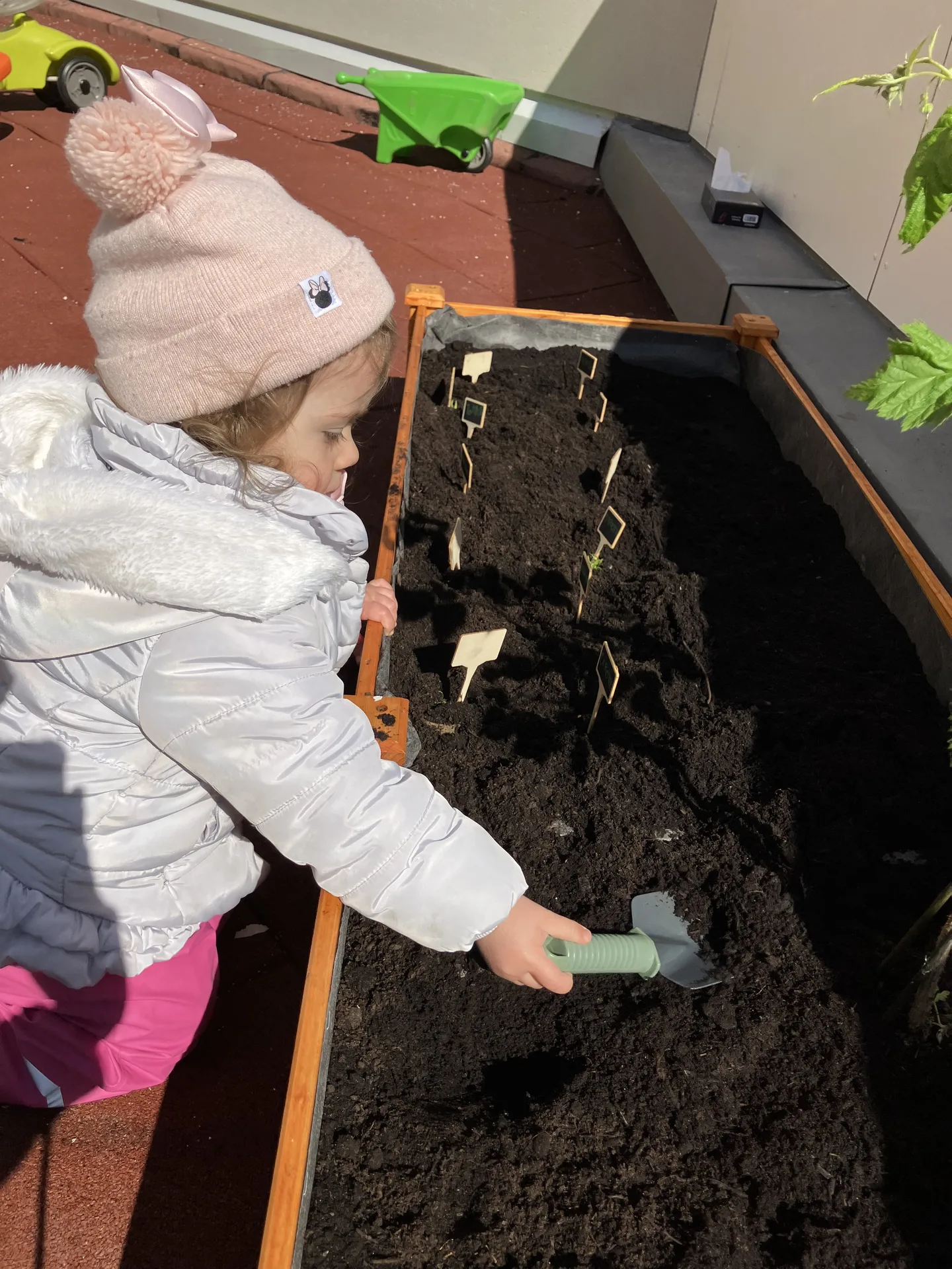 Petite jardinière au travail dans le bac potager en bois de la crèche de Differdange