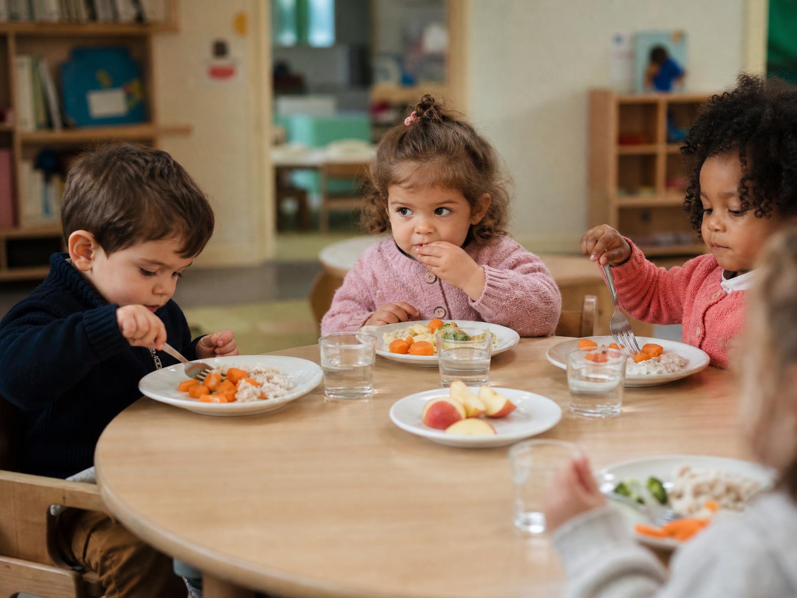 Enfants attablés en train de manger un repas équilibré à la crèche