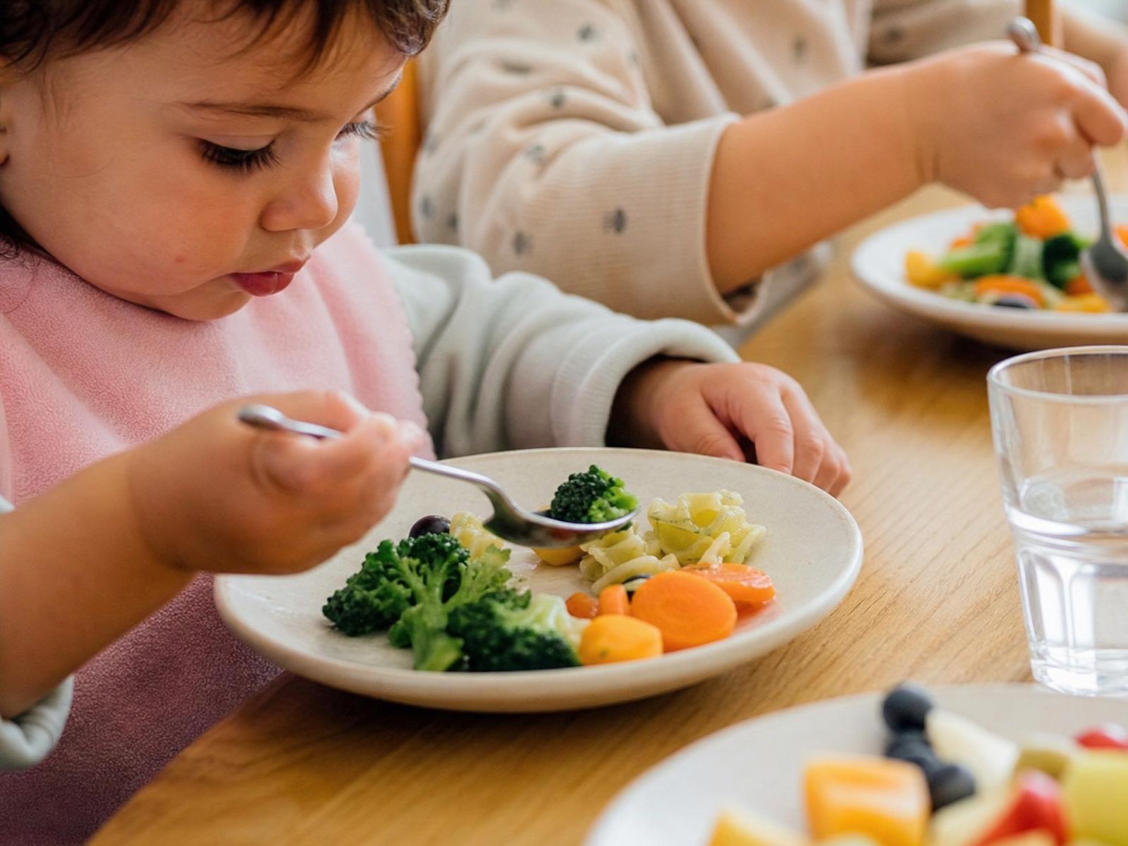 Petite fille dégustant des légumes vapeur à la crèche